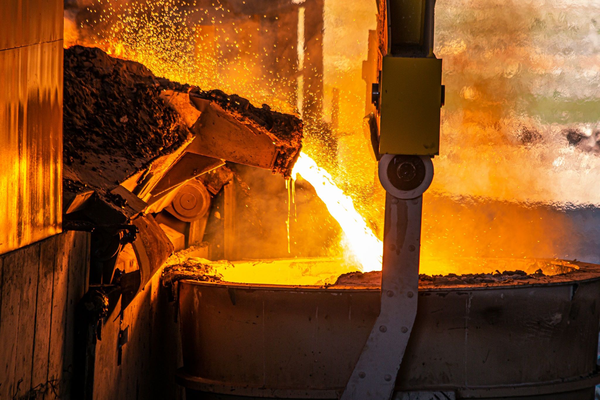 A picture of molten metal exiting the spout of a foundry into a vat