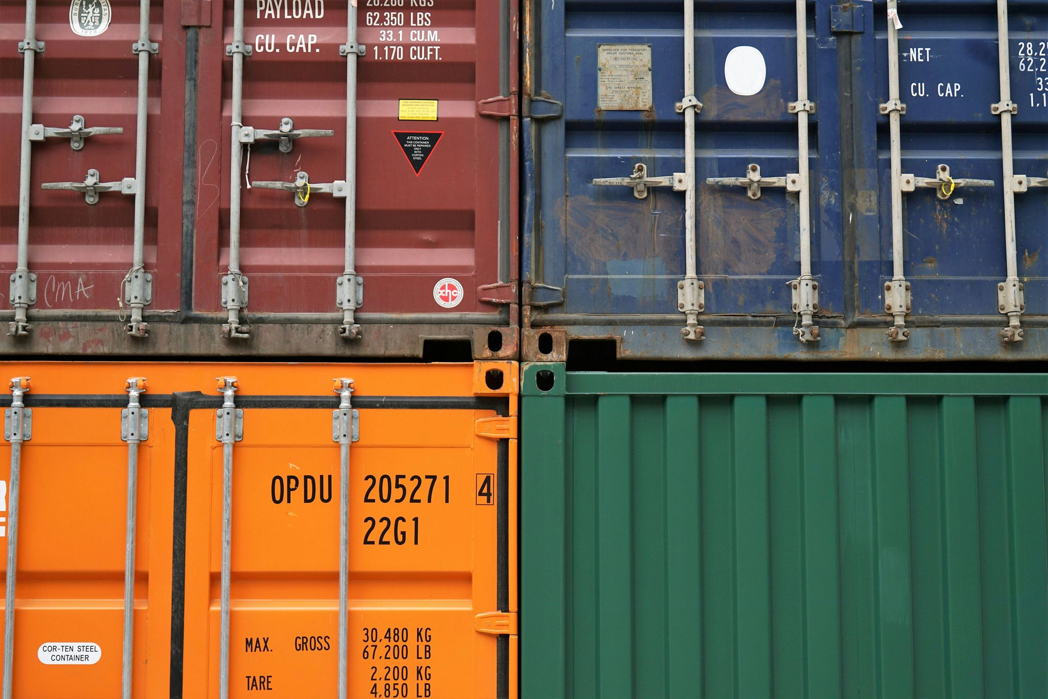 A view of four shipping containers which show some signs of rust.